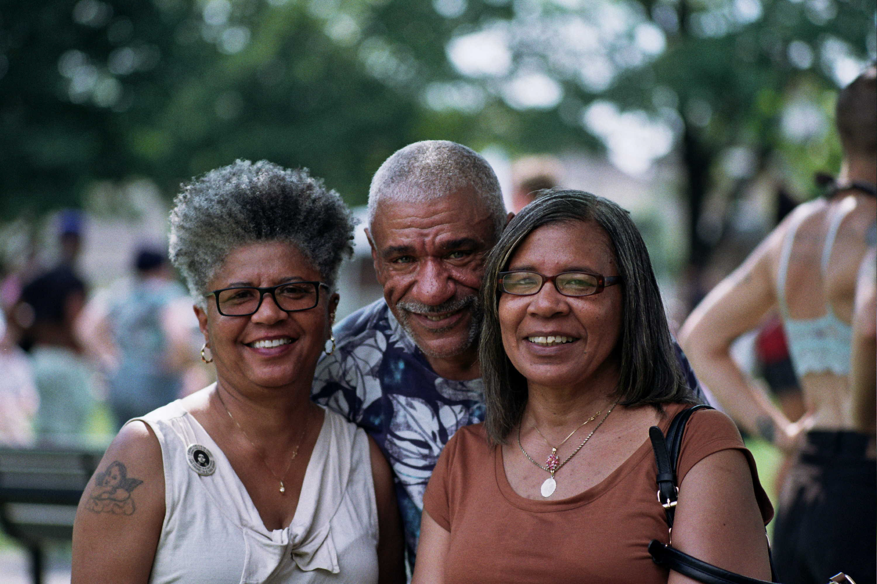 Three people gather close to smile together for the camera.